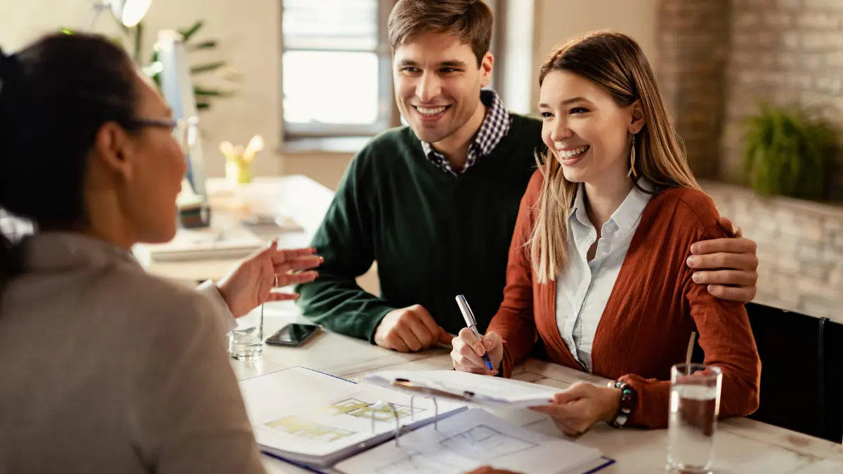 Couple reviewing home loan options with advisor using Mortgage Refinance Calculator to compare savings and refinance rates.