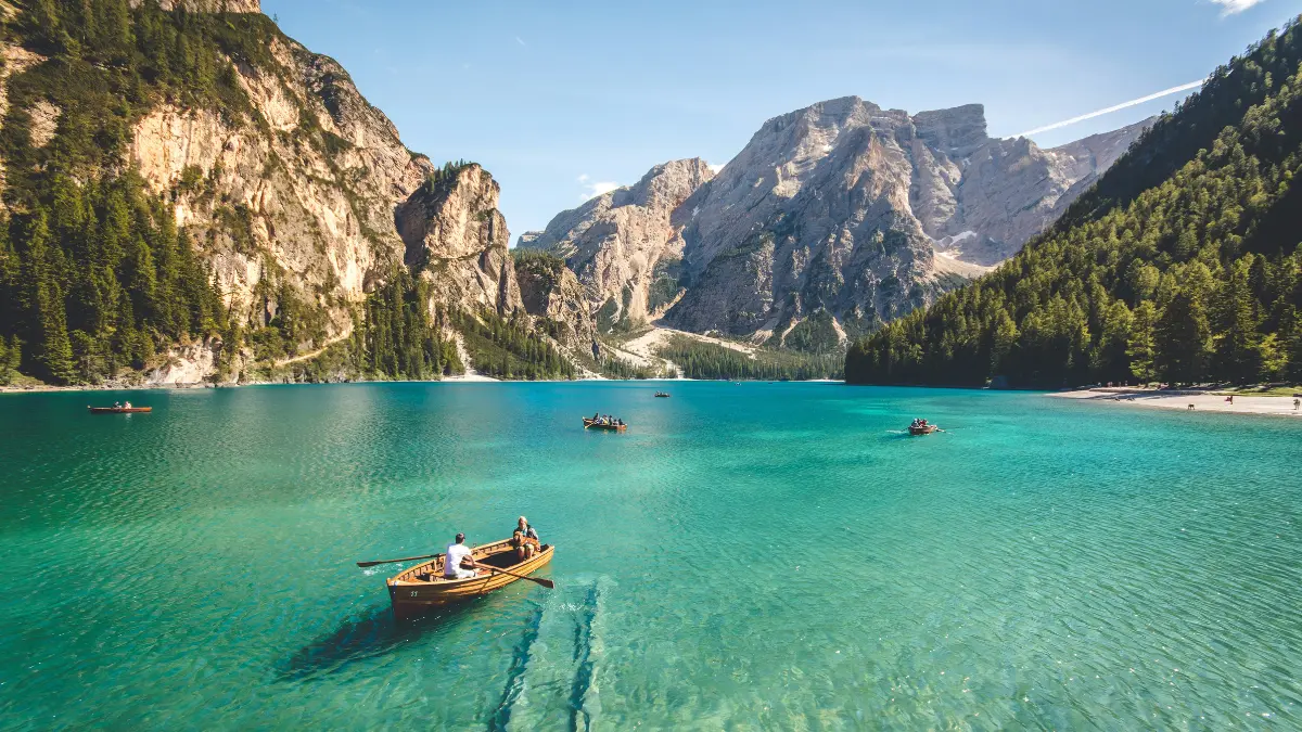 Travelers boating on alpine lake during vacation protected by Holiday insurance