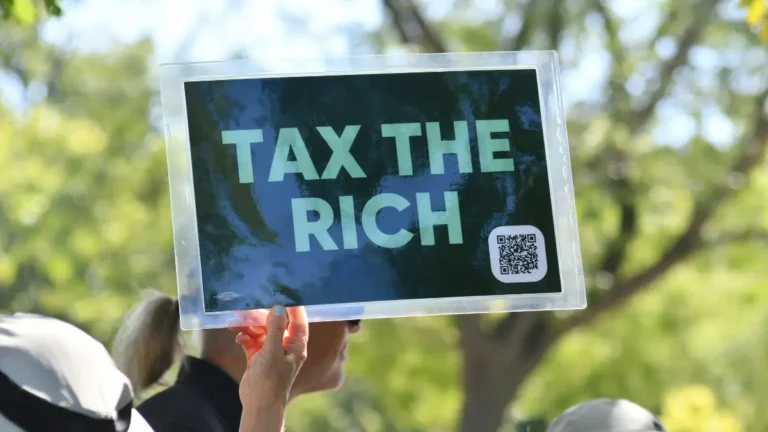 Income Tax protest sign reading tax the rich representing public debate around income tax policy and tax reform