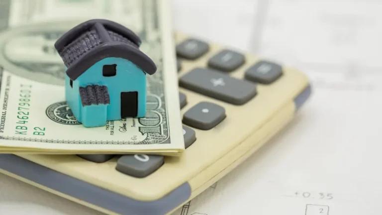 Refinance Calculator concept showing house model on dollar bills and calculator representing mortgage payment savings