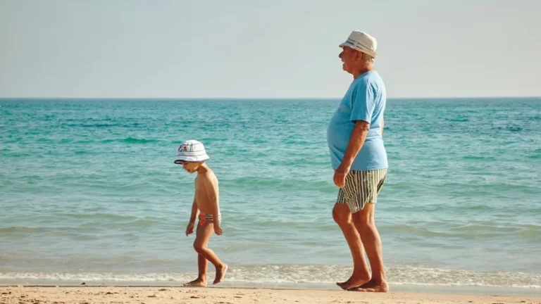 retirement calculator concept showing a retired man walking on the beach with a child symbolizing financial freedom after retirement